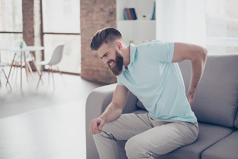 man on couch with back pain