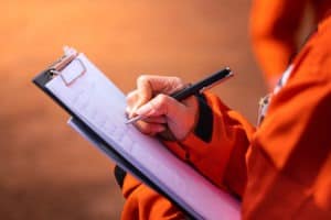 person writing on clipboard