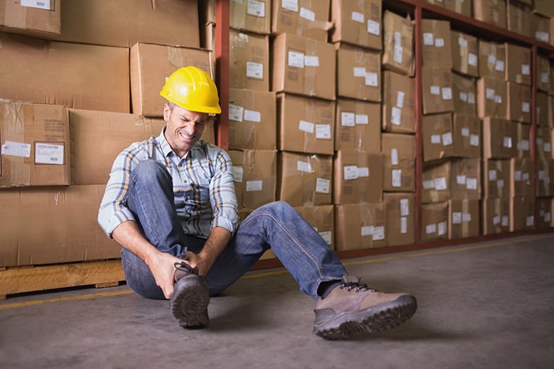 worker holding ankle in pain at work