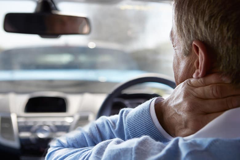 man in car with whiplash