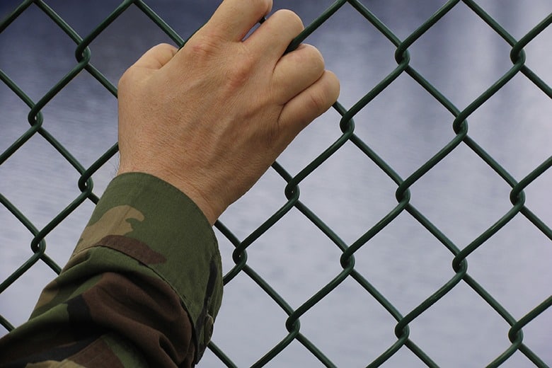 solider holding chain link fence