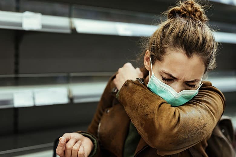 woman-wearing-mask-coughing-into-elbow