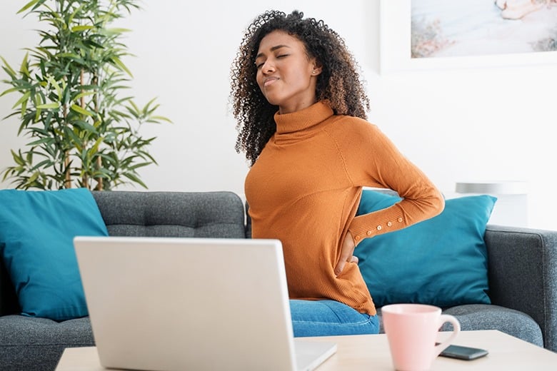 woman-with-back-pain-hand-on-back-working-from-home