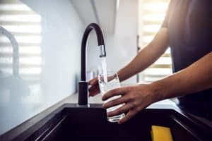 man-filling-glass-with-water-from-sink-faucet